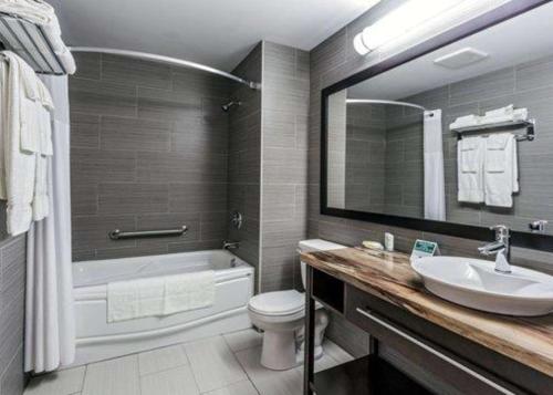 a bathroom with a sink and a tub and a toilet at Quality Inn & Suites in Matane