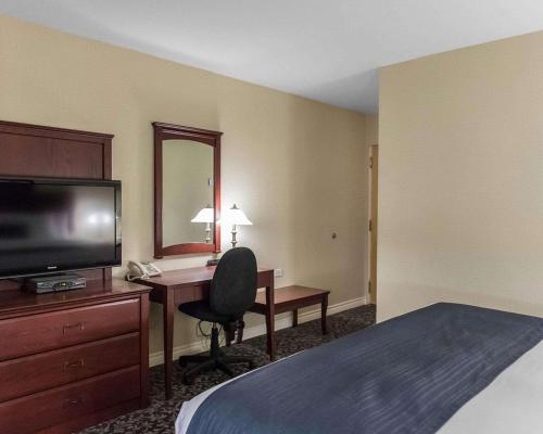 a hotel room with a desk and a bed and a television at Quality Inn Mont-Laurier in Mont-Laurier