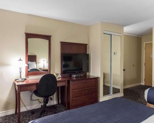 a hotel room with a desk with a television and a bed at Quality Inn Mont-Laurier in Mont-Laurier
