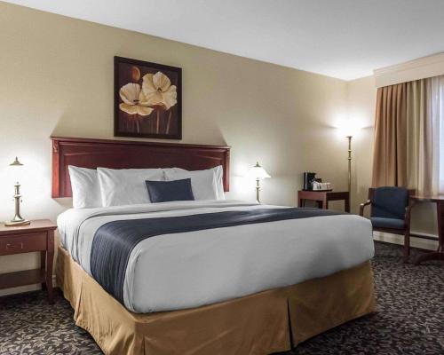 a hotel room with a large bed and a chair at Quality Inn Mont-Laurier in Mont-Laurier