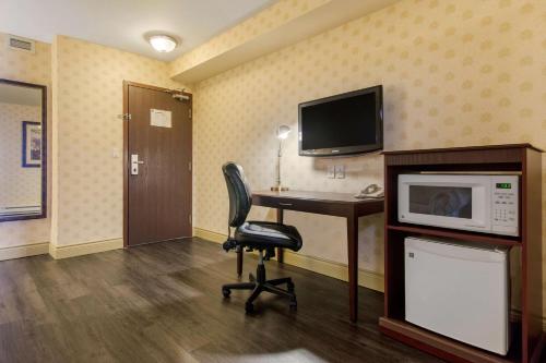 a room with a desk and a microwave and a chair at Comfort Inn & Suites in Lévis