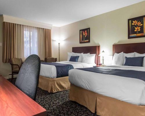 a hotel room with two beds and a desk at Quality Inn Mont-Laurier in Mont-Laurier