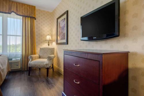 a hotel room with a dresser and a flat screen tv at Comfort Inn & Suites in Lévis