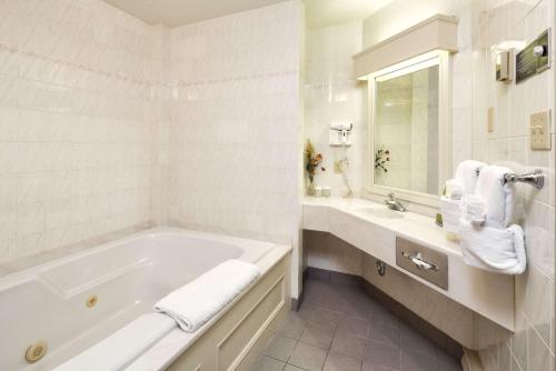 a white bath tub sitting next to a white sink at Inn on the Lake, Ascend Hotel Collection in Fall River
