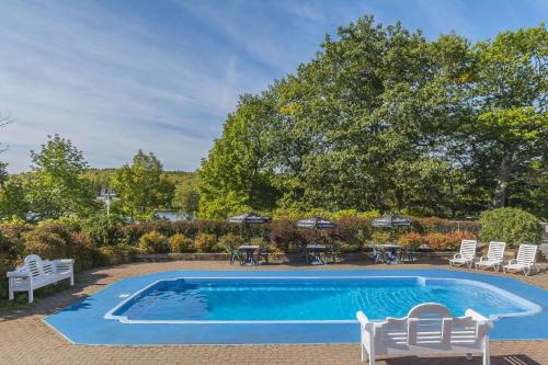 a swimming pool with chairs and a table and trees at Inn on the Lake, Ascend Hotel Collection in Fall River