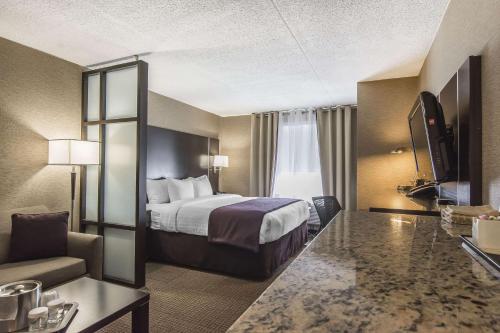 Habitación de hotel con cama, sofá y TV en Quattro Hotel & Conf. Centre, Ascend Hotel Collection, en Sault Ste. Marie