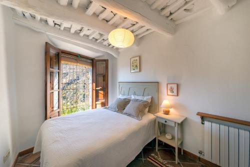 a bedroom with a white bed with a window at Casa La Parra in Capileira