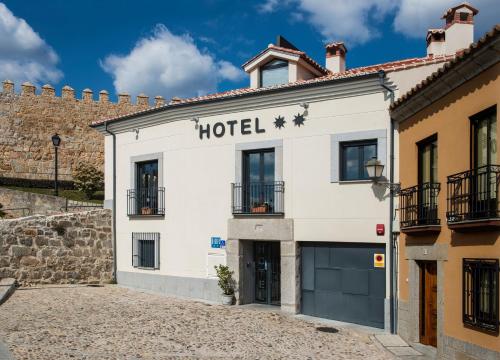 Hotel Puerta de la Santa في أفيلا: مبنى ابيض عليه لافته الفندق