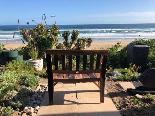 un banco de madera sentado junto a la playa en Sea Paradise, en Wilderness