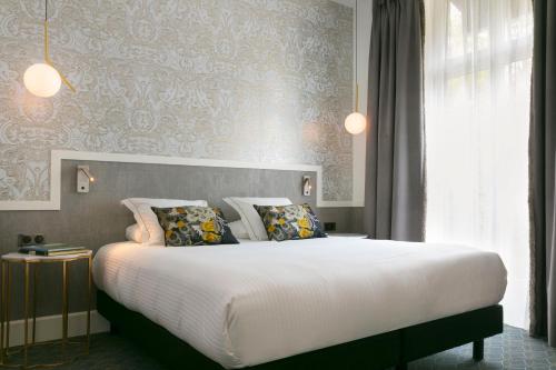 a bedroom with a large white bed with pillows at Continental Hotel in Reims