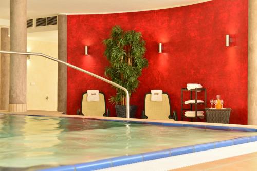 a swimming pool with chairs and a red wall at Autenrieder Gästehaus Schlossbräu in Autenried