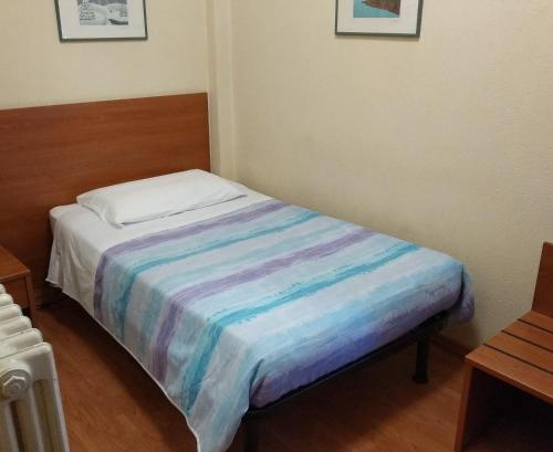 a small bedroom with a bed with a colorful blanket at Hotel Lucciola in Bordighera