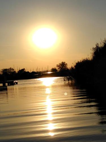 a sunset over a river with the sun setting at Pfahlbau Sunset I Toplage Elektroboot inklusive in Rust