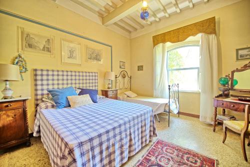a bedroom with a bed and a desk and a window at Villa Elisa by PosarelliVillas in Cortona