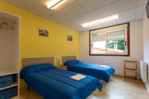 two beds in a room with yellow walls at A taberna de vento in Lalín