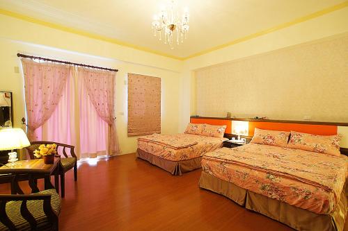Habitación de hotel con 2 camas y lámpara de araña. en Garden Rose Homestay, en Taitung