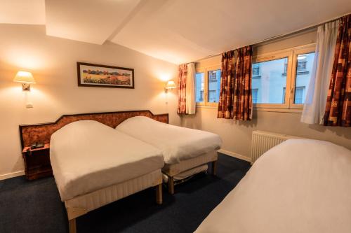 a hotel room with two beds and a window at Hôtel Neptune Place d'Italie in Paris