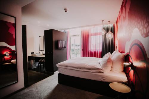 a bedroom with a large bed with a red wall at Hotel & Restaurant Heyligenstaedt in Gießen