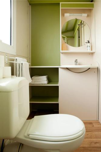 a bathroom with a white toilet and a mirror at Camping Os Fieitás in O Grove