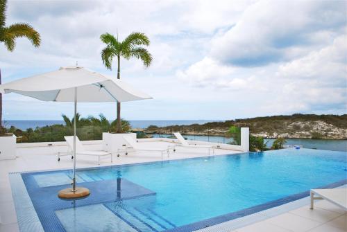 a swimming pool with chairs and an umbrella at Piscadera Harbour Village in Willemstad