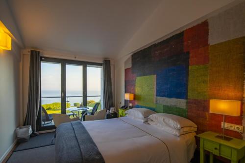 a bedroom with a large bed with a colorful wall at Hotel Arbe in Mutriku