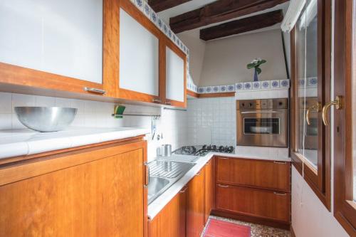 eine Küche mit Holzschränken und einem Waschbecken in der Unterkunft Cà della Regina in Venedig