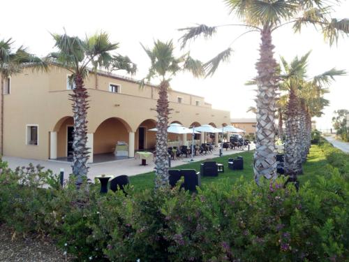 a row of palm trees in front of a building at Hotel Donna Carmela Sede Unica a Sciacca in Sciacca