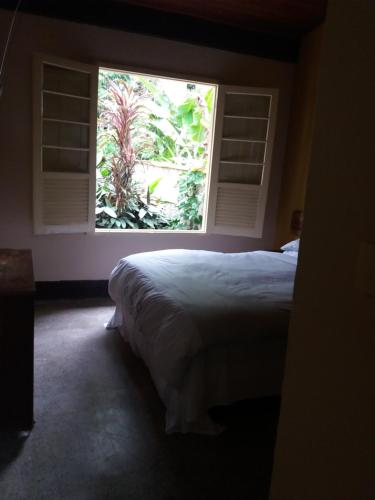 a bedroom with a large bed and a window at "Chalé Balines Oroboro" 1 - Casa com jardim de 150 m e cozinha completa em Macacos in Macacos