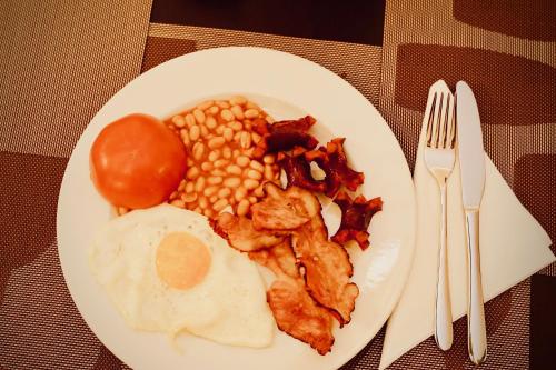 a plate of breakfast food with eggs beans and tomatoes at Astoria Hotel & SPA in Hunedoara