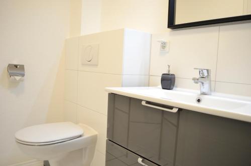 a white bathroom with a toilet and a sink at Hana Aparthotel in Hamburg