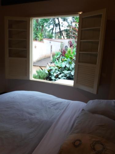 a bedroom with a window looking out at a garden at "Chalé Balines Oroboro" 1 - Casa com jardim de 150 m e cozinha completa em Macacos in Macacos