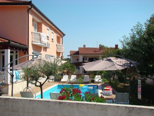 a swimming pool with an umbrella next to a building at Apartments Kimm in Poreč