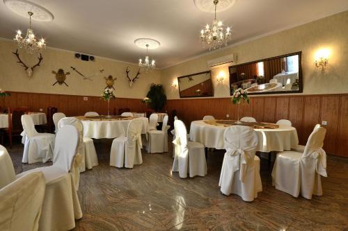 a banquet room with white tables and white chairs at Zajazd Zagłoba in Widoma