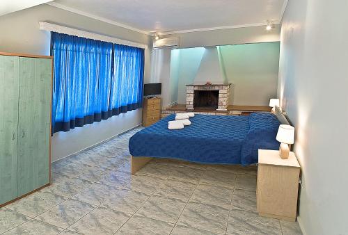 a bedroom with a blue bed and a fireplace at Villa Magemenou in Nikiana
