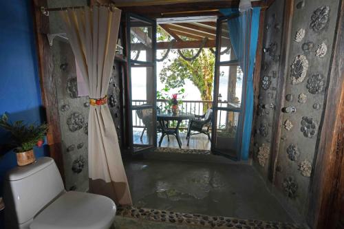 a bathroom with a toilet and a balcony with a table at Ecolodge el Arca Bahia Solano in Bahía Solano
