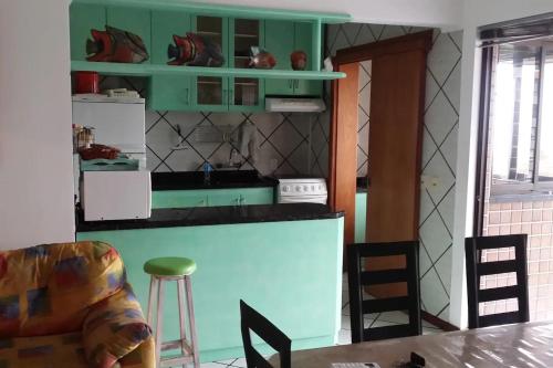 una cocina con armarios verdes, mesa y sillas en APTO c VISTA MARAVILHOSA DO MAR, PERTO DA PRAIA, en Torres
