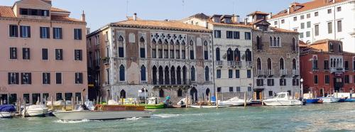 un gruppo di imbarcazioni nell’acqua accanto agli edifici di Palazzo Morosini Brandolin Dimora Romantica a Venezia