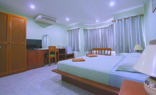 Schlafzimmer mit einem Bett, einem Schreibtisch und einem TV in der Unterkunft Green Island Guesthouse in Karon Beach