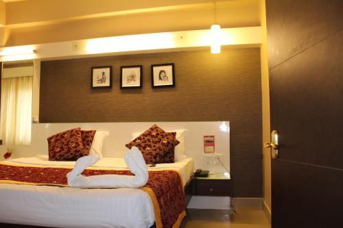 a hotel room with a bed with two swansuddlesigunigunigunigun at Hotel Pooja International in Dāvangere