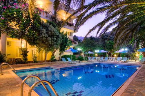una piscina di fronte a un hotel di notte di Sunrise Hotel & Apartments a Rodakino