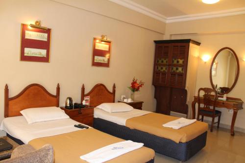 a hotel room with two beds and a mirror at Hotel Pooja International in Dāvangere