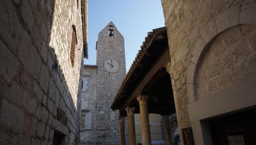 a building with a clock tower in an alley at Apartment Lavanda garden in Rab