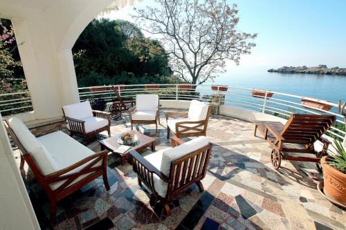 a group of chairs and tables on a patio overlooking the water at Royal Holiday Apartments Sveti Stefan in Sveti Stefan