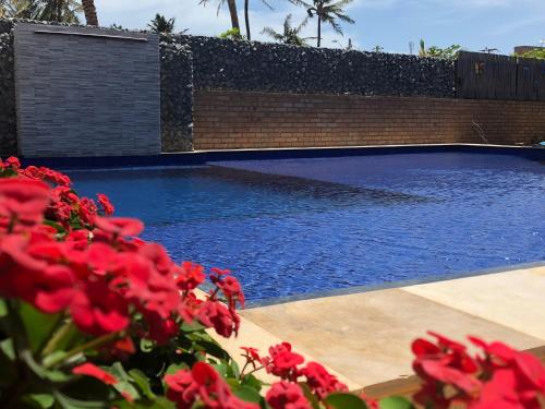 a swimming pool with red flowers in front of it at Pousada Casa Do Alemão in Flecheiras