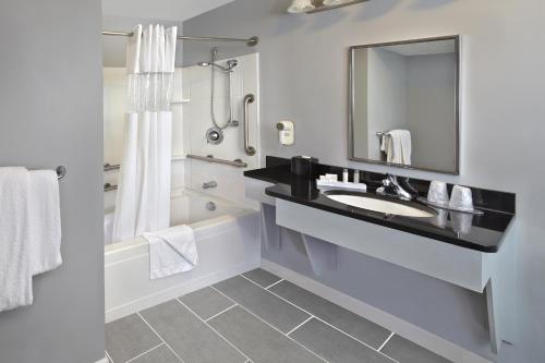 ein Badezimmer mit einem Waschbecken, einer Badewanne und einem Spiegel in der Unterkunft New Haven Village Suites in New Haven
