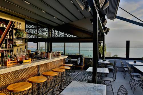 a bar with wooden stools and a view of the ocean at Wes Hotel in Kocaeli