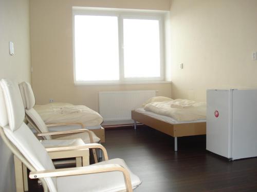 a room with three beds and chairs and a refrigerator at Ubytovací areál Rouchovany in Rouchovany