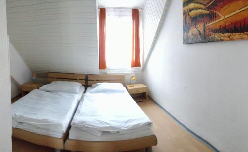 2 Betten in einem kleinen Zimmer mit Fenster in der Unterkunft Picobello Herberge in Görlitz