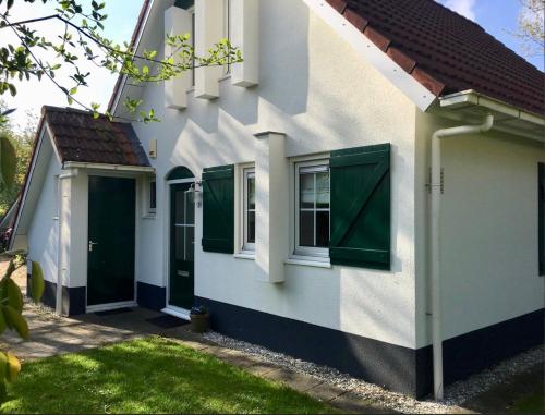 a white house with green doors and a yard at Vakantiewoning 'Eysinga State' in Sint Nicolaasga