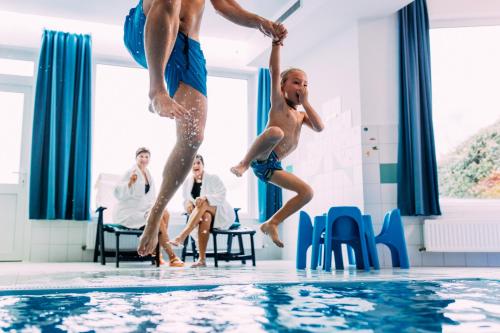Dois homens a saltar para uma piscina. em Pitzis Kinderhotel - Family Only em Arzl im Pitztal